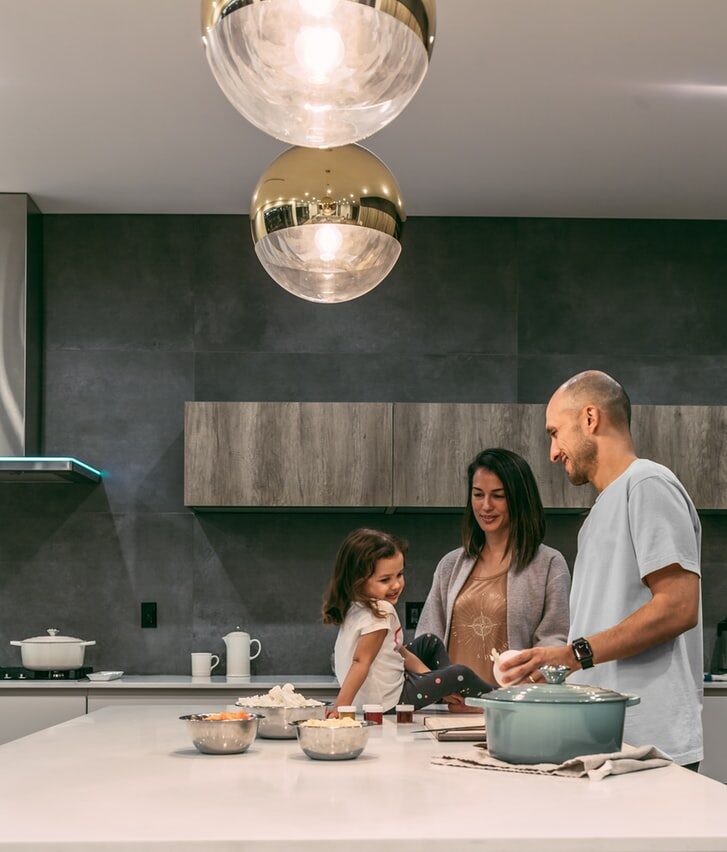 Smiling family preparing a meal together in a modern kitchen with pendant lighting