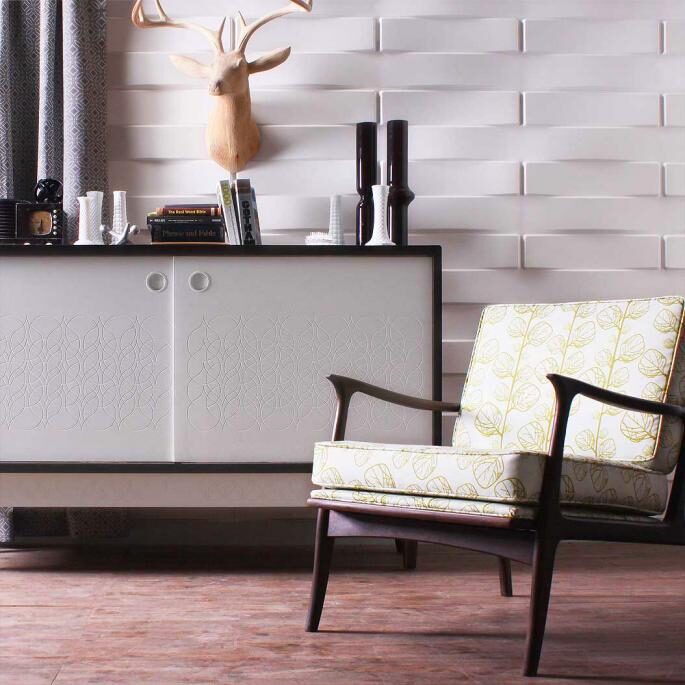 Room featuring white 3-dimensional wall panels behind a modern sideboard and an accent chair